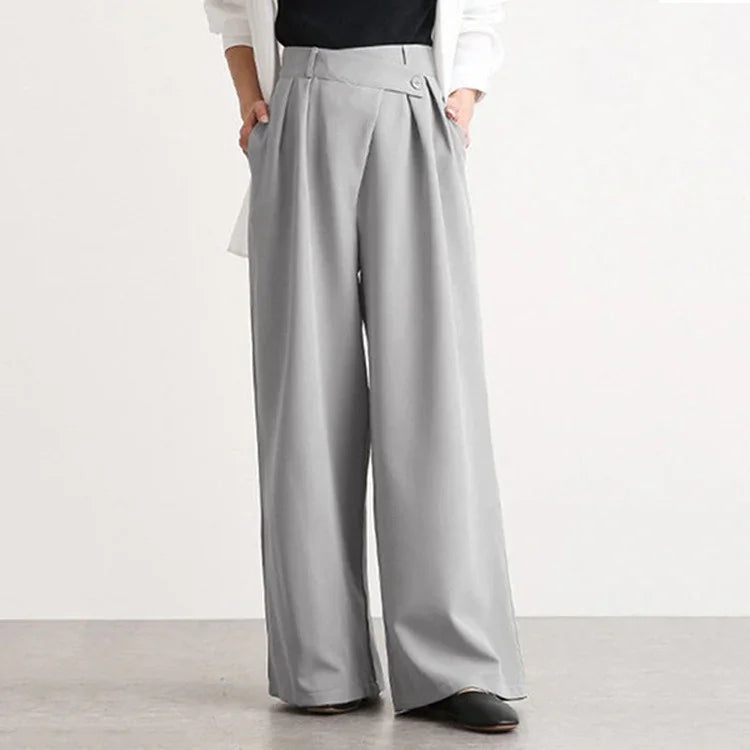 Gray wide-leg trousers with front pleats and button detail worn with black shoes and a white top