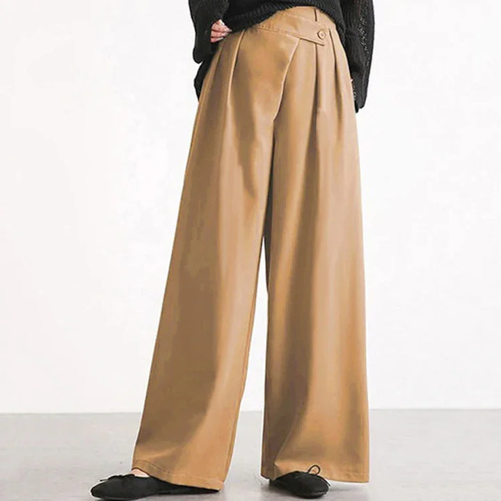 Wide-leg high-waist tan trousers with button detail, paired with black sweater and flats