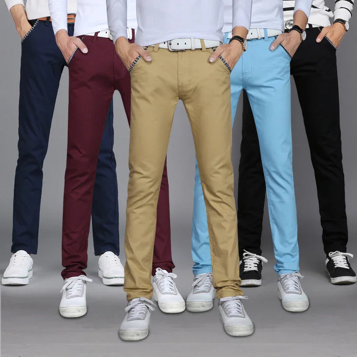 Men wearing slim fit casual pants in navy, burgundy, khaki, light blue, and black with white sneakers