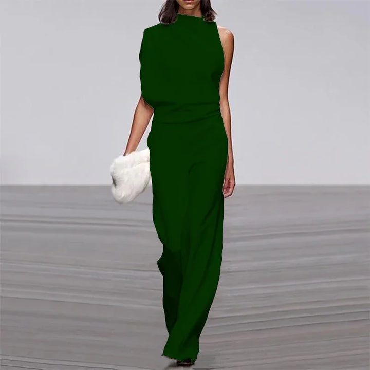 Fashion model in sleeveless dark green jumpsuit carrying white fluffy clutch on runway