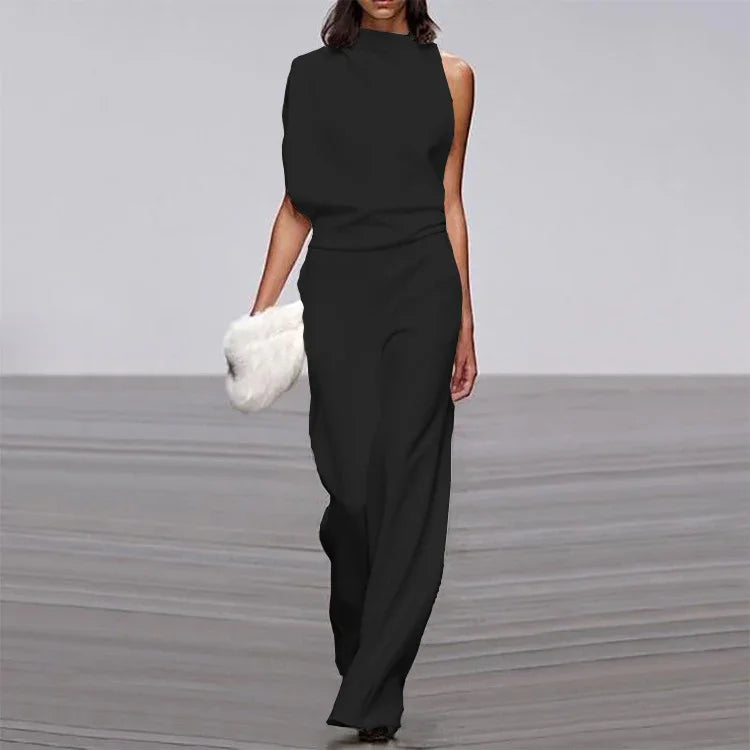 Fashion model in black sleeveless asymmetrical jumpsuit holding white furry clutch on runway