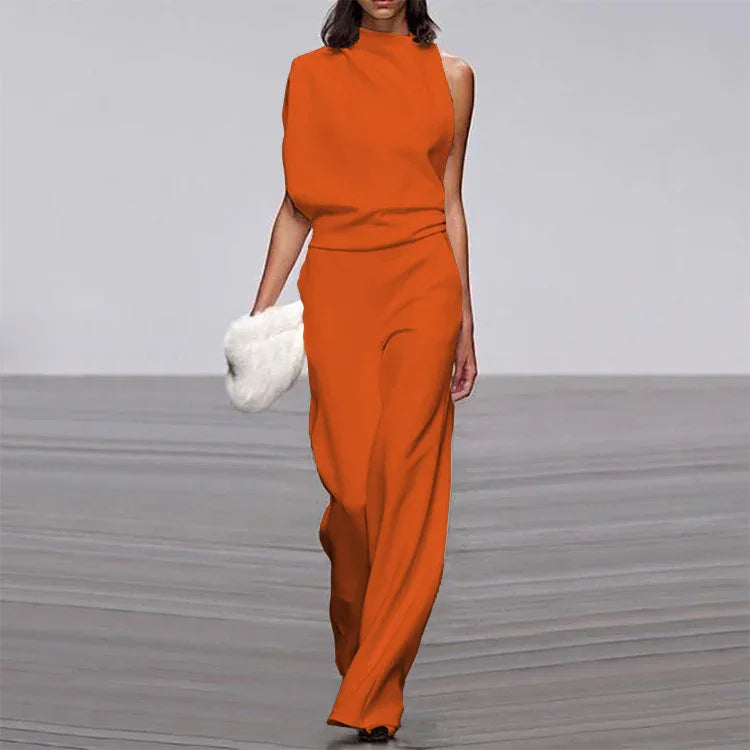 Model walking runway in sleeveless orange jumpsuit holding white fur clutch bag