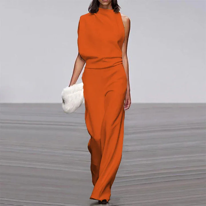 Model walking runway in sleeveless orange jumpsuit holding white fur clutch bag