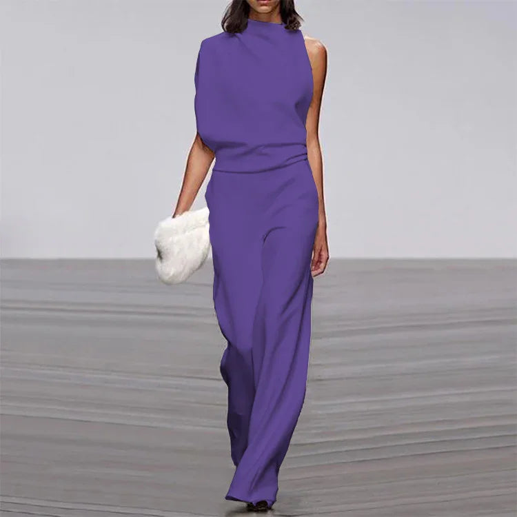Fashion model walking runway in purple sleeveless jumpsuit holding white fluffy clutch