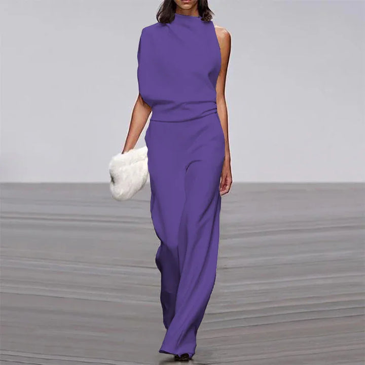 Fashion model walking runway in purple sleeveless jumpsuit holding white fluffy clutch