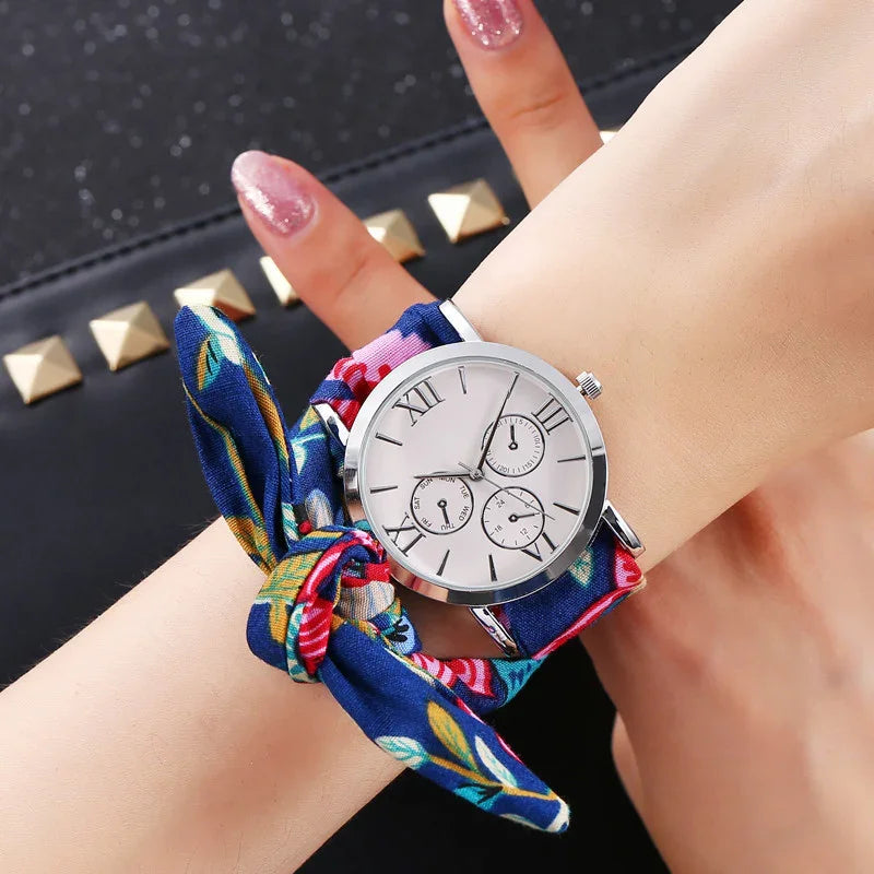 Silver wristwatch with white dial and Roman numerals on wrist wrapped in blue floral fabric band