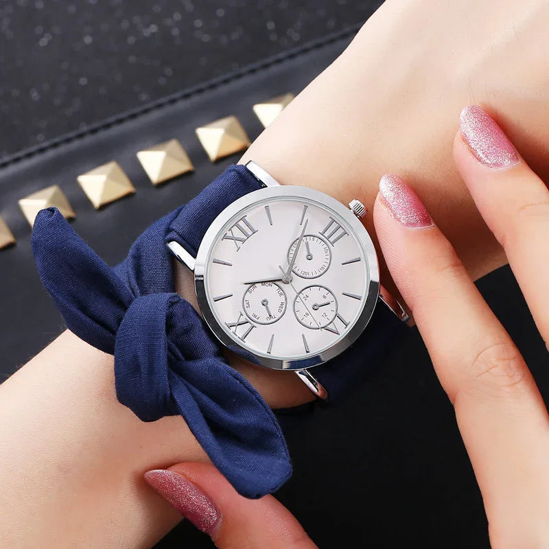 Elegant wristwatch with white dial and Roman numerals on navy blue fabric band, worn on wrist
