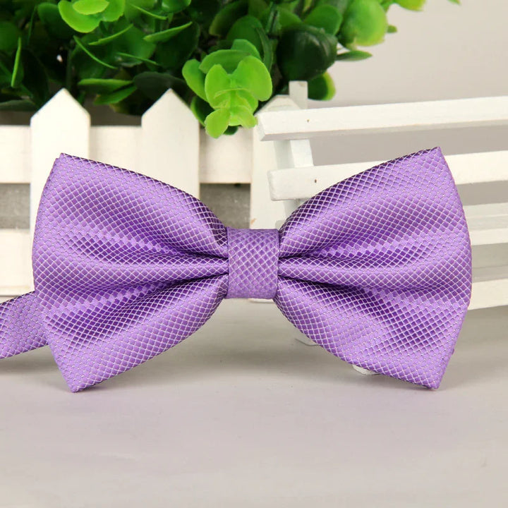 Elegant purple textured satin bow tie displayed with green plant and white picket fence background