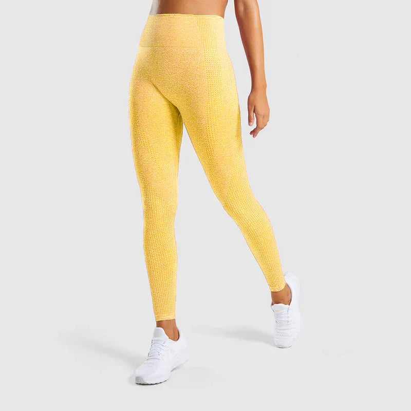 Woman wearing yellow textured high-waist leggings and white athletic shoes on gray background
