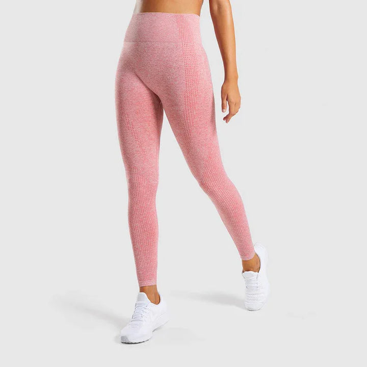 Woman wearing pink textured seamless high-waisted leggings and white sneakers on gray background