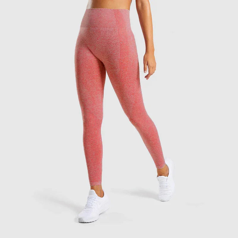Woman wearing high-waist seamless pink leggings and white sneakers on gray background
