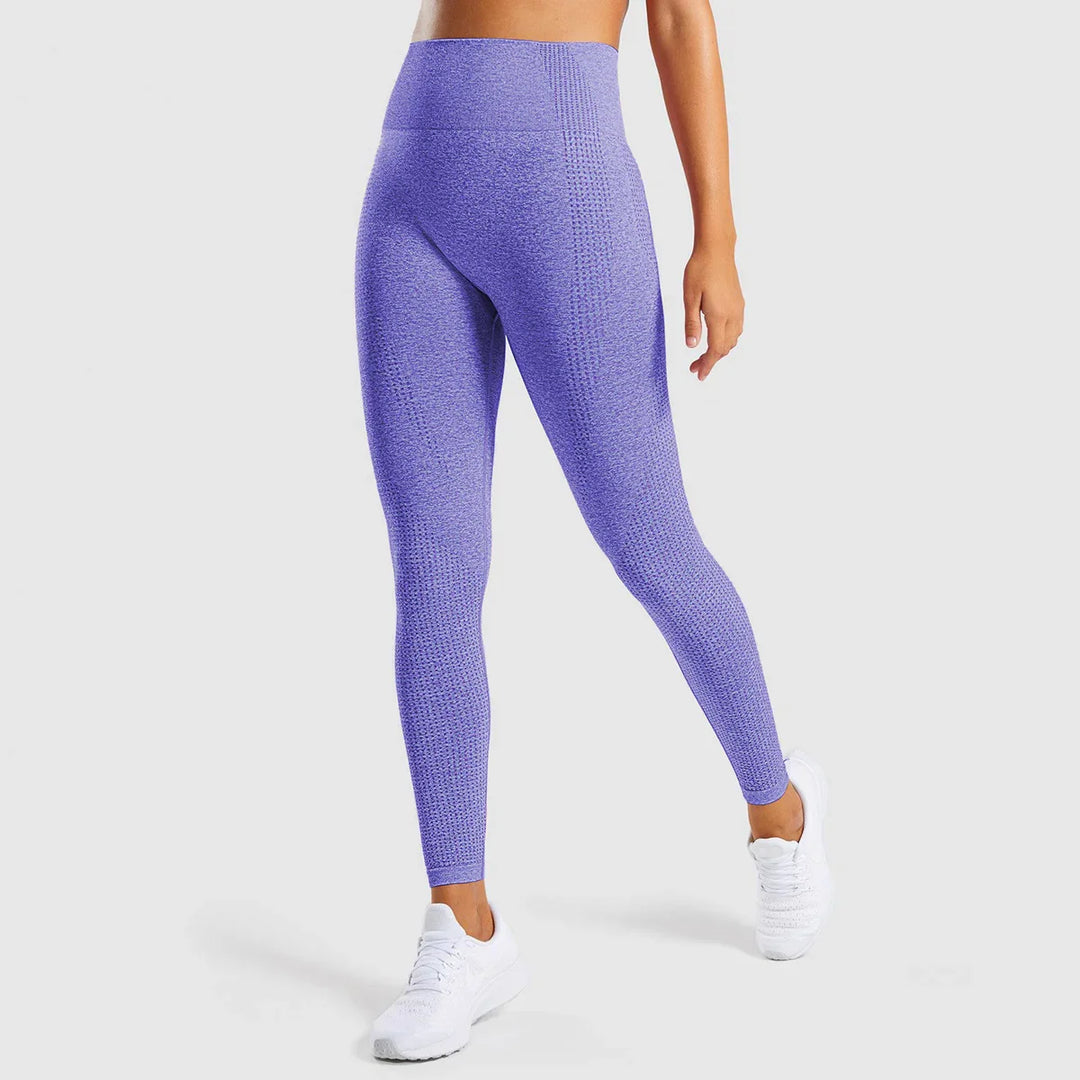 Woman wearing high-waisted seamless purple leggings and white sneakers on white background