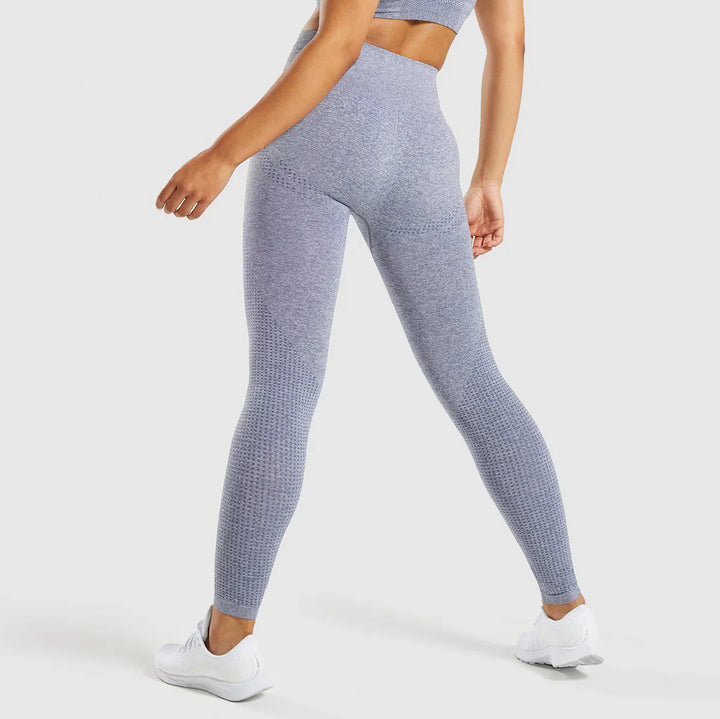Woman wearing seamless grey high-waisted textured leggings and white athletic shoes, back view