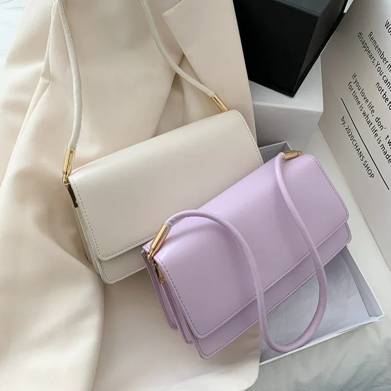 Elegant small shoulder bags in pastel lavender and cream with gold hardware on soft fabric