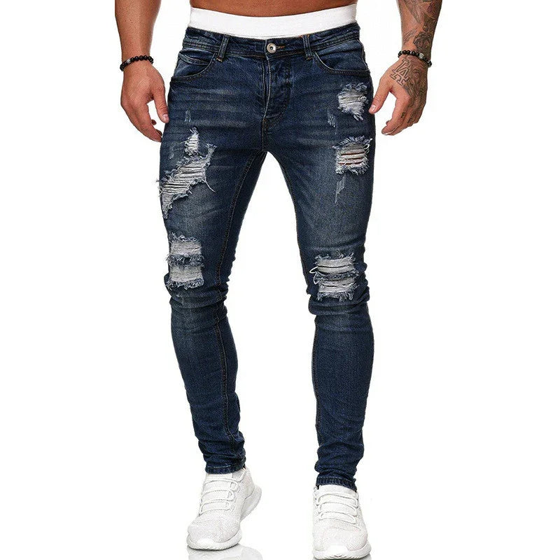 Mens dark blue ripped skinny jeans paired with white sneakers on a model against white background