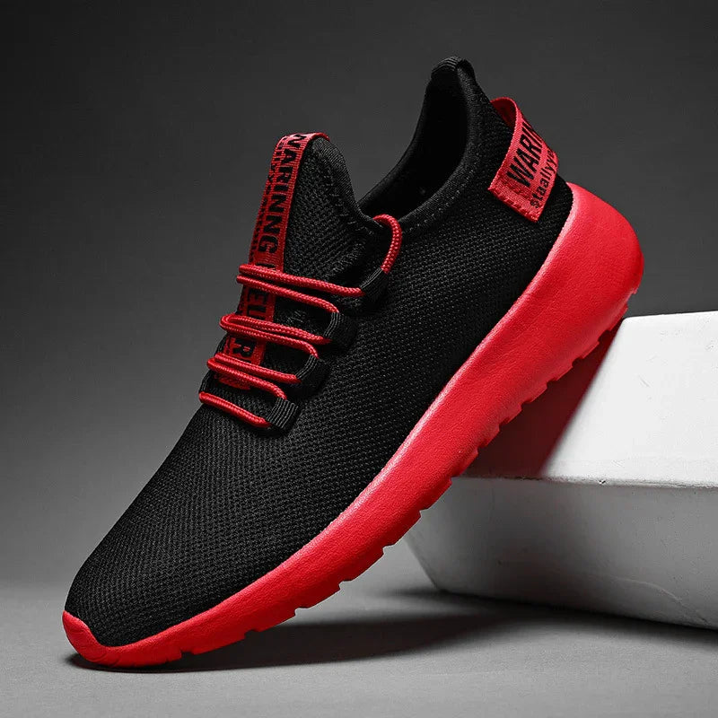 Black and red lightweight athletic sneaker with mesh upper, red sole, and red laces on gray background