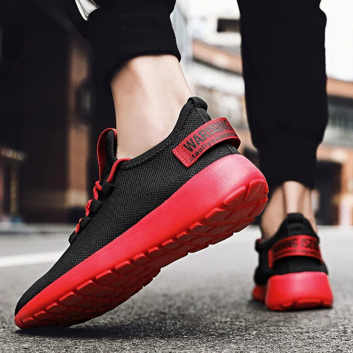 Close-up of black and red athletic sneakers with thick red soles worn by person walking outdoors