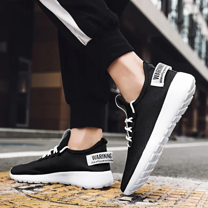 Close-up of black and white sporty sneakers with white laces on urban pavement