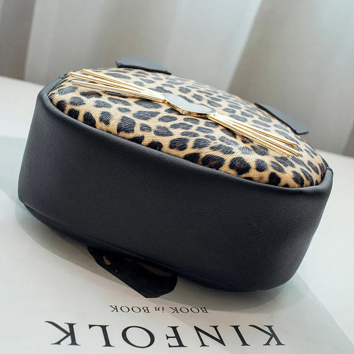 Round leopard print bag with black leather sides and gold cat whisker detail on Kinfolk book