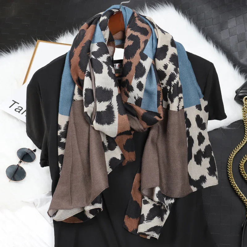 Leopard print scarf with blue and brown blocks draped over black shirt on hanger