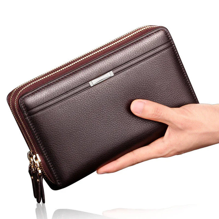 Hand holding a dark brown leather wallet with double zipper and card slots