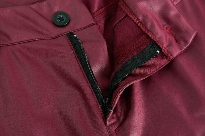 Close-up of maroon pants featuring a black zipper and a single black button closure