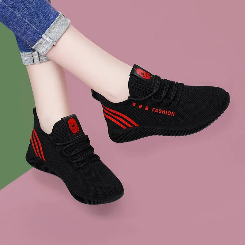 Black mesh sneakers with red stripes and fashion text worn with rolled-up jeans on pink and green background