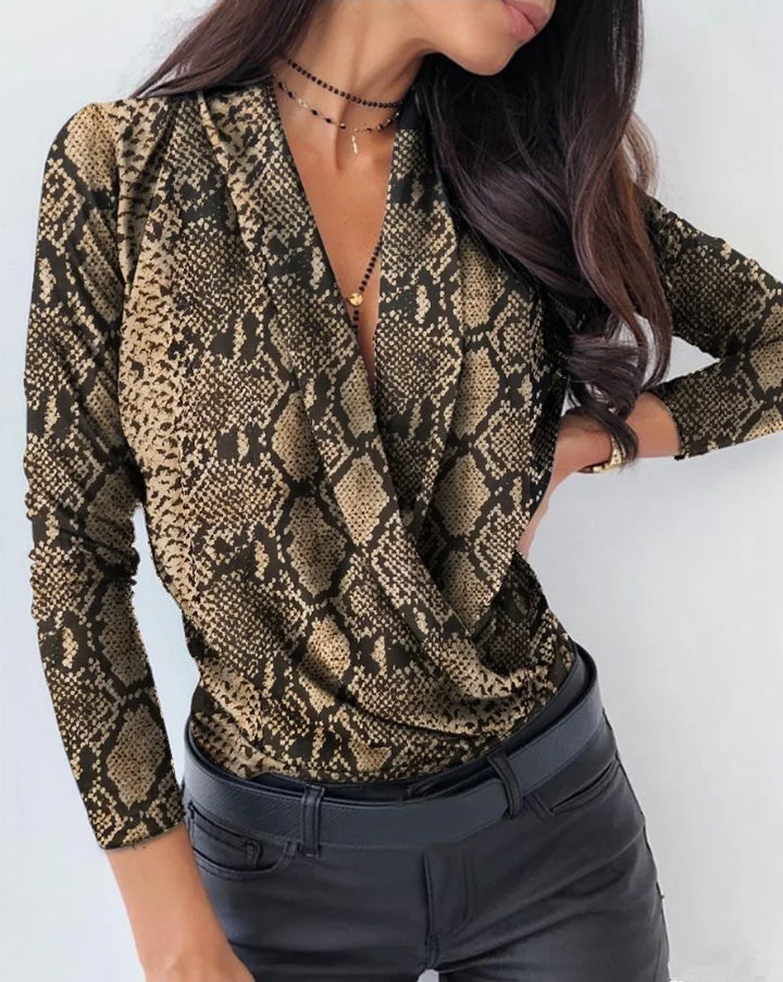 Woman wearing snake print long sleeve wrap top with black pants and layered necklaces
