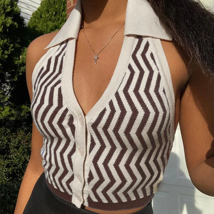 Close-up of a woman wearing a brown and white zigzag sleeveless knit top with buttons and a cross necklace