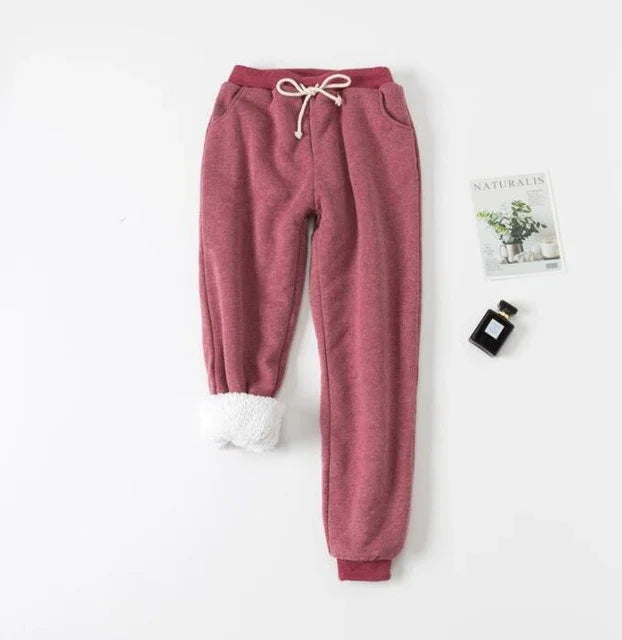 cozy pink fleece jogger pants with white sherpa lining on cuff, drawstring waist, flat lay with magazine and perfume