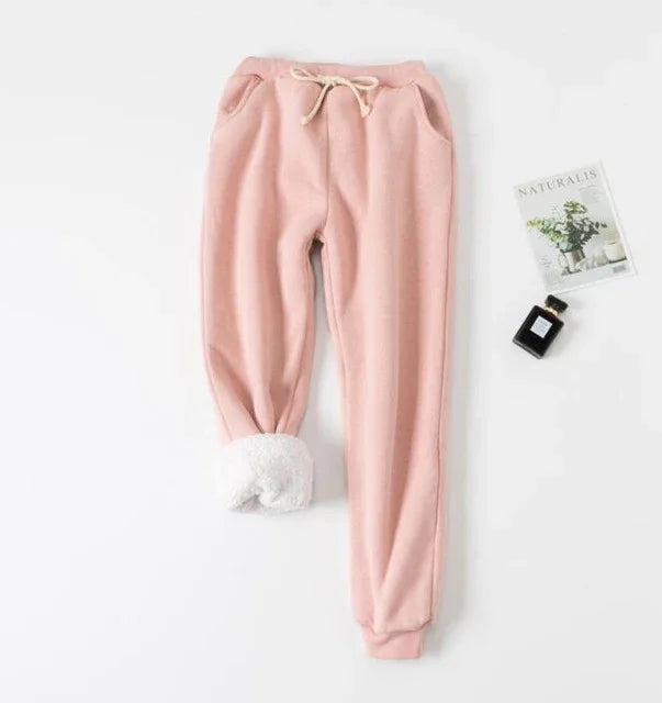 Soft pink fleece sweatpants with drawstring waist and white plush cuffs displayed flat on white background