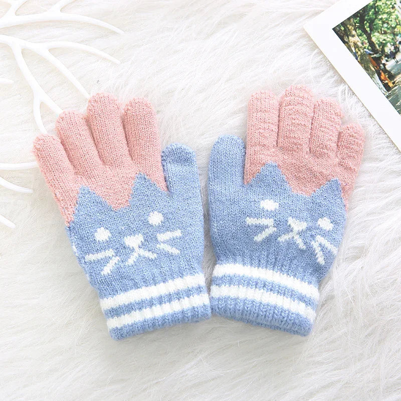 Cute knitted gloves with blue cat face and pink fingers, cozy winter accessory on white fur background