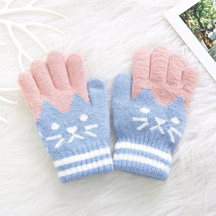 Cute knitted gloves with blue cat face and pink fingers, cozy winter accessory on white fur background