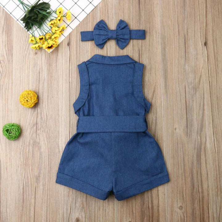 Blue denim sleeveless baby romper with matching bow headband on wooden surface