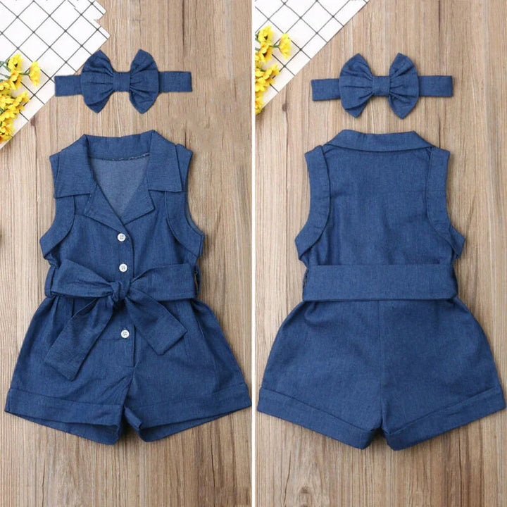 Blue sleeveless romper with buttons and belt, paired with matching bow headband on wooden background