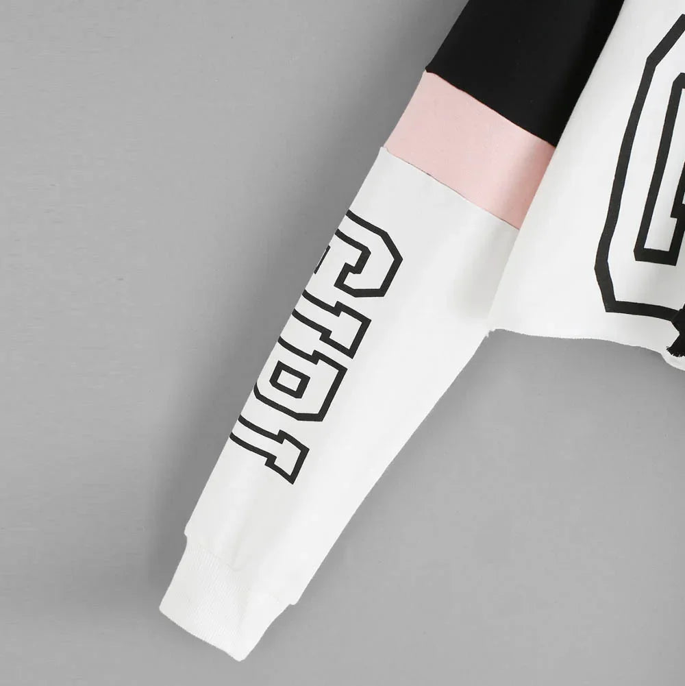 Sleeve of color-block sweatshirt with black, pink, and white panels and black outlined lettering