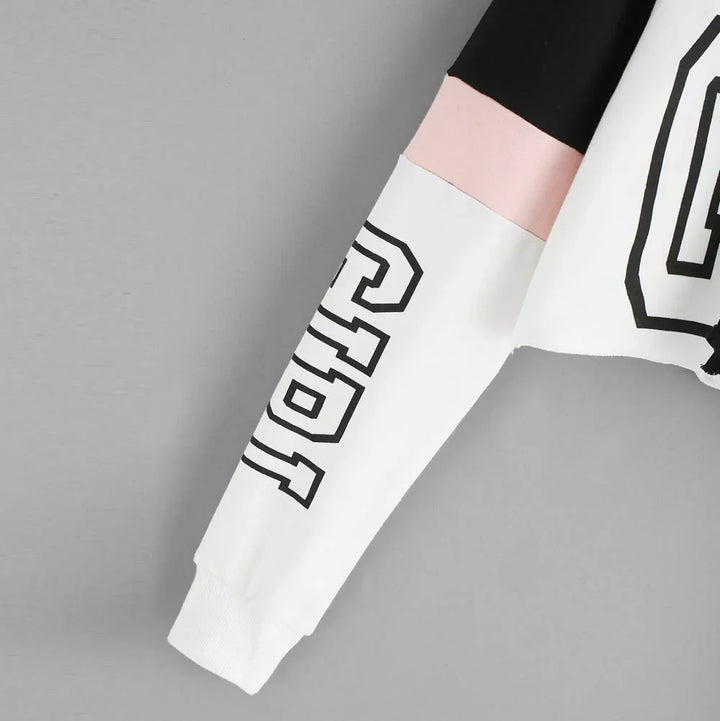 Sleeve of color-block sweatshirt with black, pink, and white panels and black outlined lettering