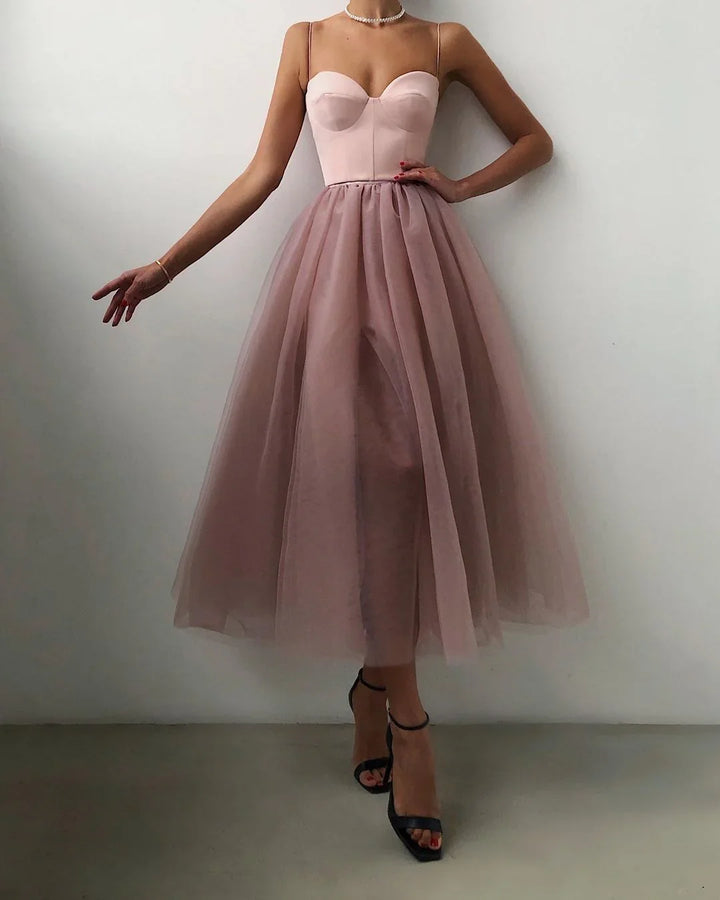 Woman wearing a pink strapless bodice dress with a full tulle midi skirt and black ankle-strap heels