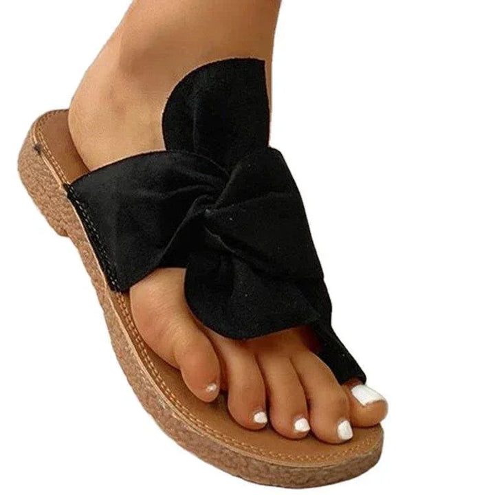 Black bow espadrille sandal on foot with white toenail polish and cork sole