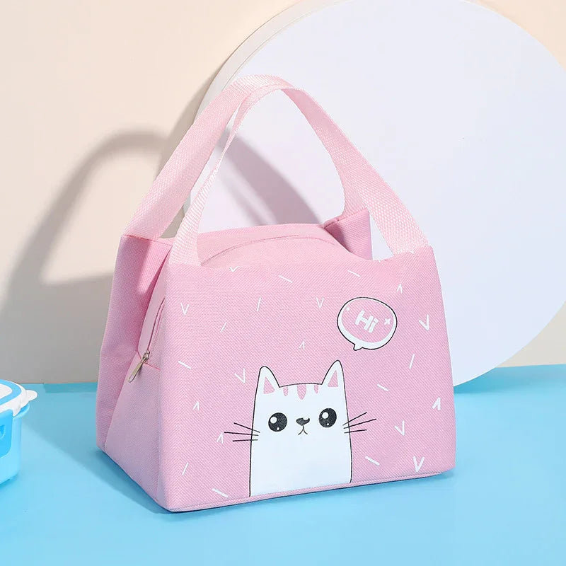 Pink lunch bag with cute white cat illustration and speech bubble saying 'Hi' on blue surface
