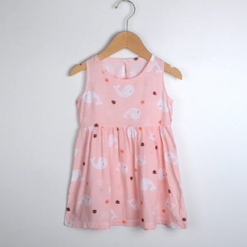 Pink sleeveless toddler dress with white whale and sea-themed prints hanging on wooden hanger