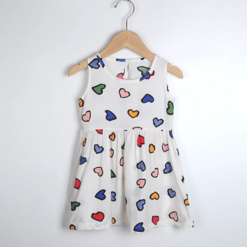 White sleeveless toddler dress with colorful heart prints hanging on wooden hanger