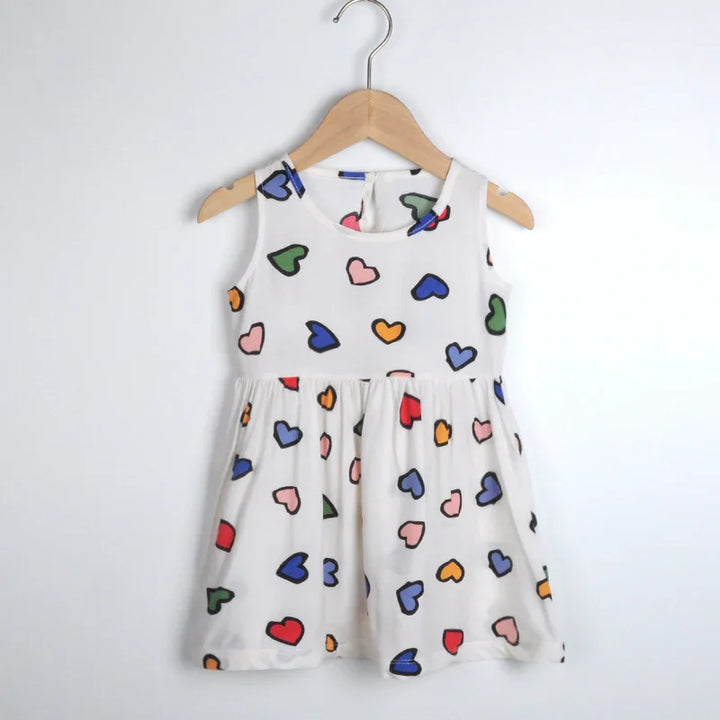 White sleeveless toddler dress with colorful heart prints hanging on wooden hanger