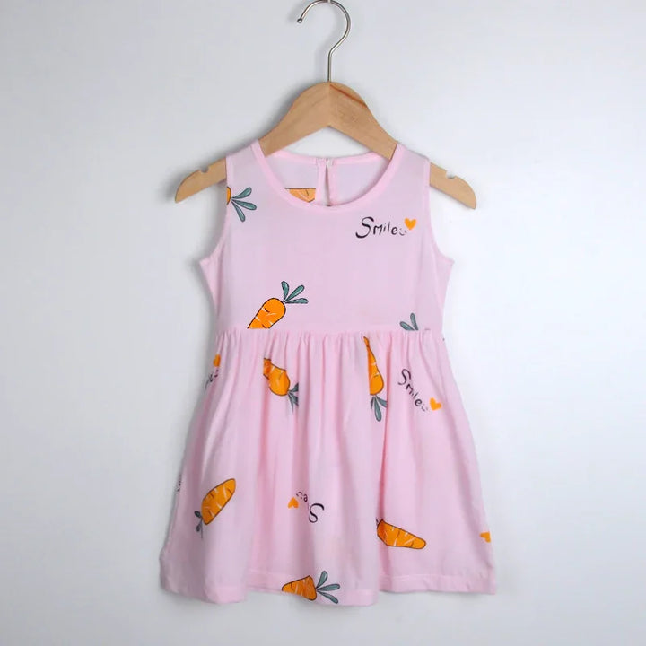 Pink sleeveless toddler dress with carrot prints and 'Smile' text hanging on wooden hanger