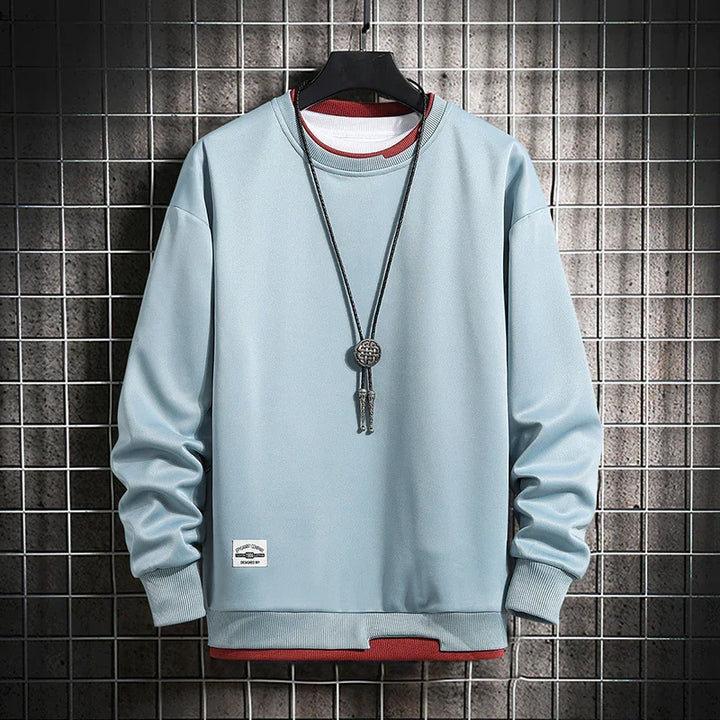 Light blue long-sleeve sweatshirt layered over red shirt, hanging on black hanger with a black pendant necklace