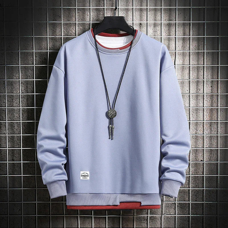 Light purple crewneck sweatshirt layered over red and white shirts with a long pendant necklace on black hanger