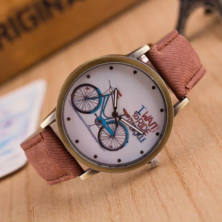 Vintage wristwatch with brown fabric strap and bicycle graphic on white dial with I want to ride my bicycle text