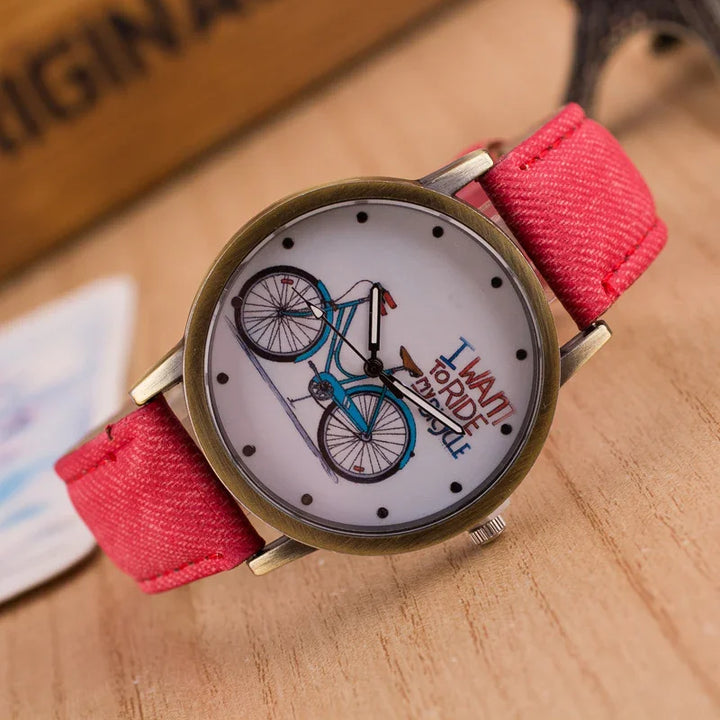 Vintage wristwatch with red strap featuring a blue bicycle and 'I want to ride my bicycle' text on white dial