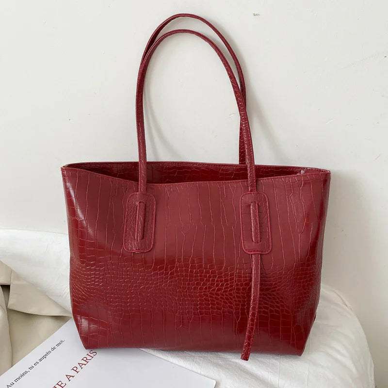 Red crocodile texture leather tote bag with double handles on white cloth background