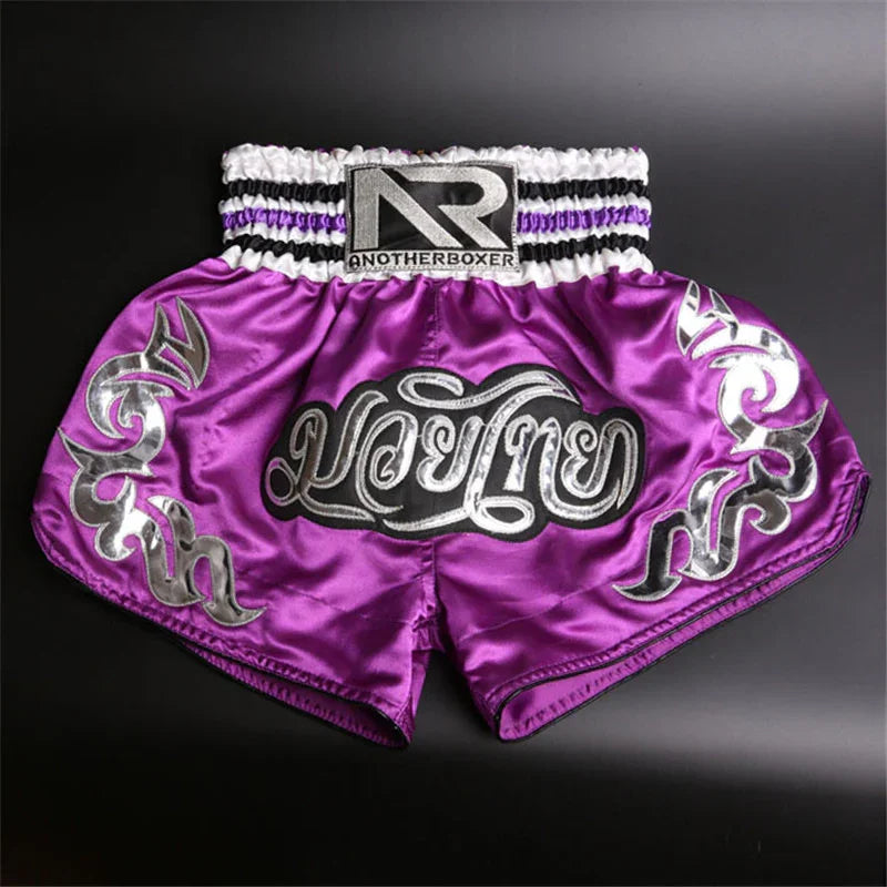 Purple satin Muay Thai boxing shorts with silver Thai script and AnotherBoxer logo on waistband